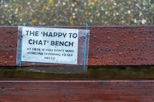 Bench with sign inviting sit and say hello.